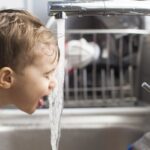 Bambino beve acqua del rubinetto con osmosi inversa in modo sicuro