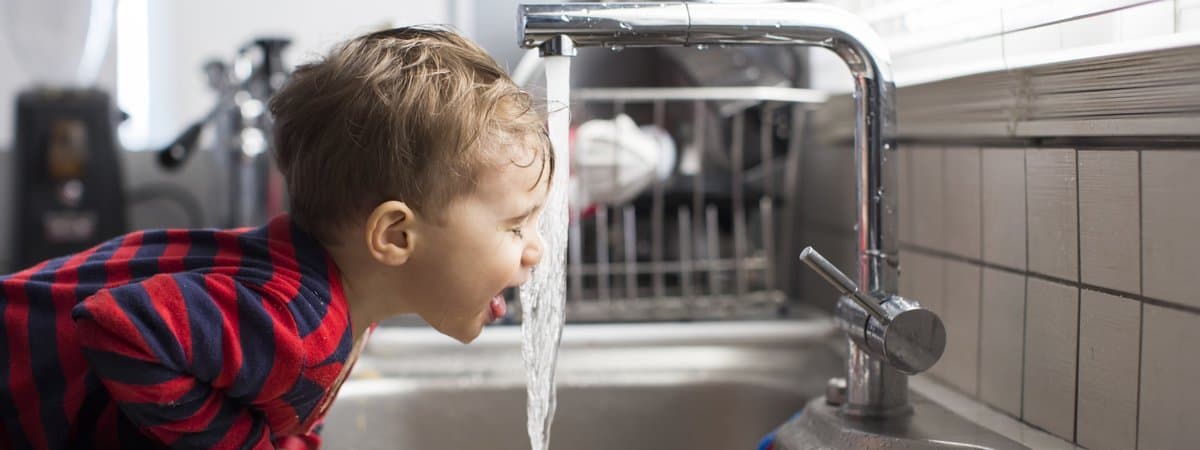 Bambino beve acqua del rubinetto con osmosi inversa in modo sicuro